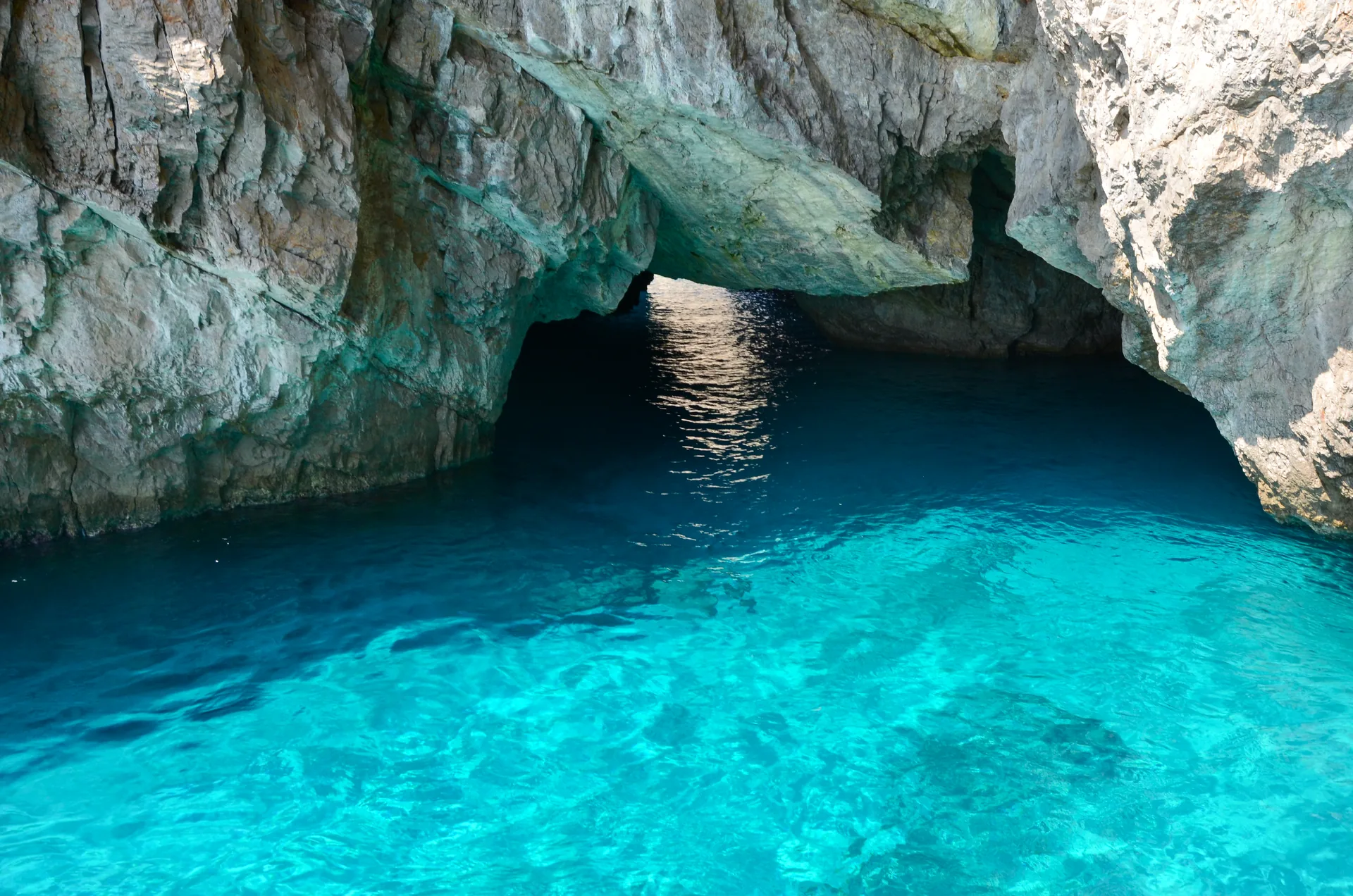 Água azul-turquesa dentro da Gruta Verde, sob paredões de calcário, na ilha de Capri, na Itália