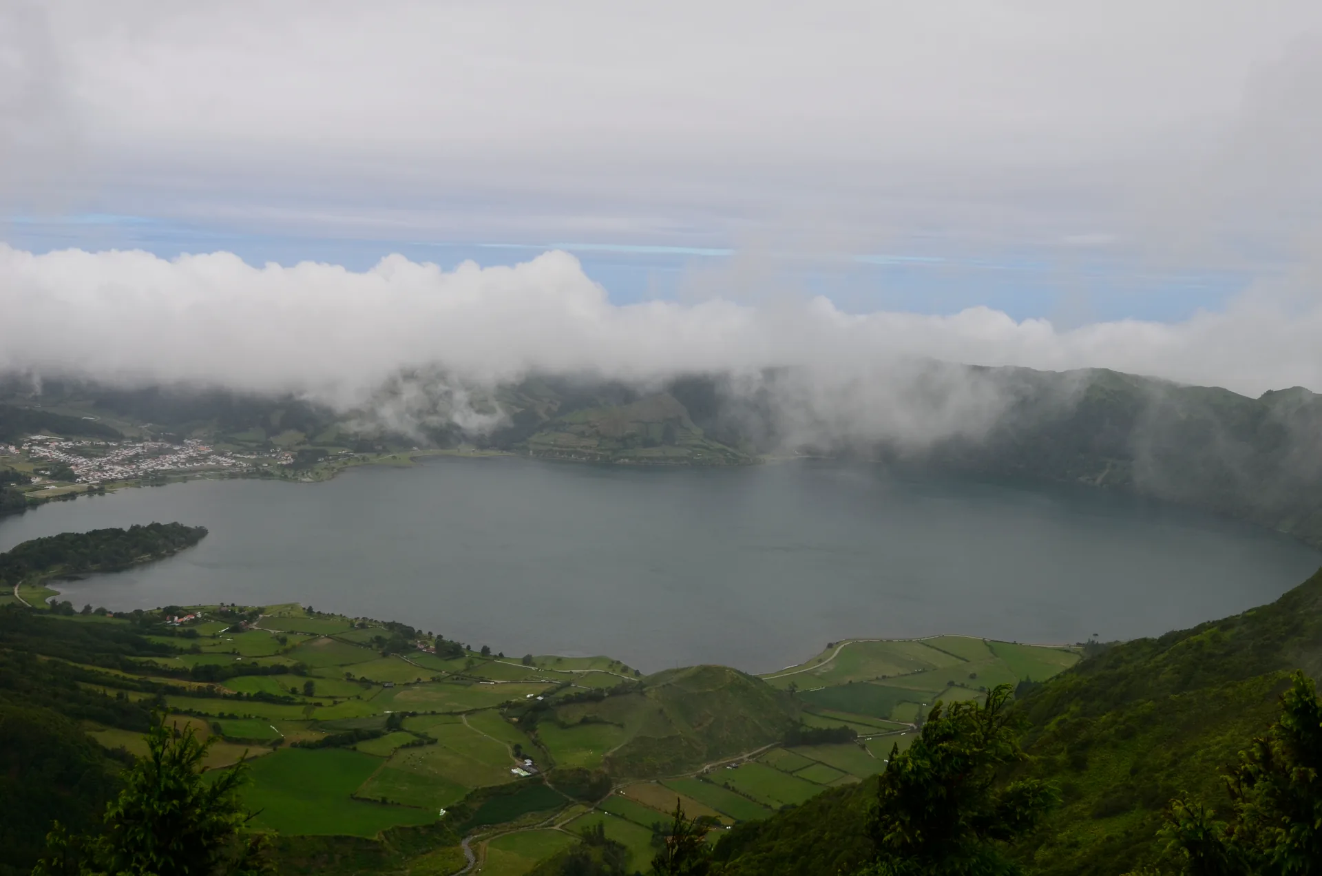 Lagoa das Sete Cidades no fundo de uma cratera verde, sob nuvens baixas, na Ilha de São Miguel, nos Açores