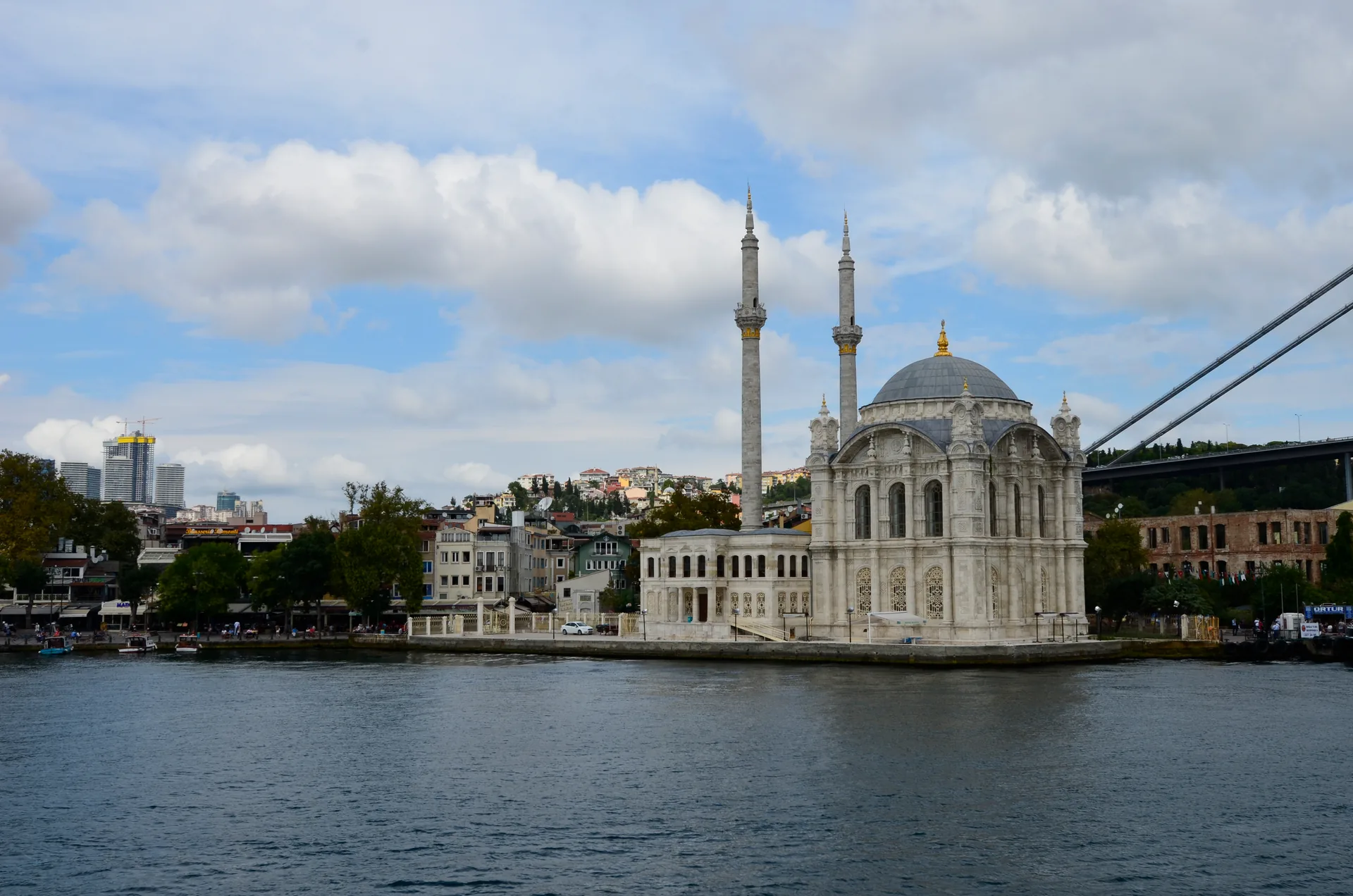 Mesquita de Ortaköy, branca e com dois minaretes, à beira do Bósforo, em Istambul, com a ponte ao fundo