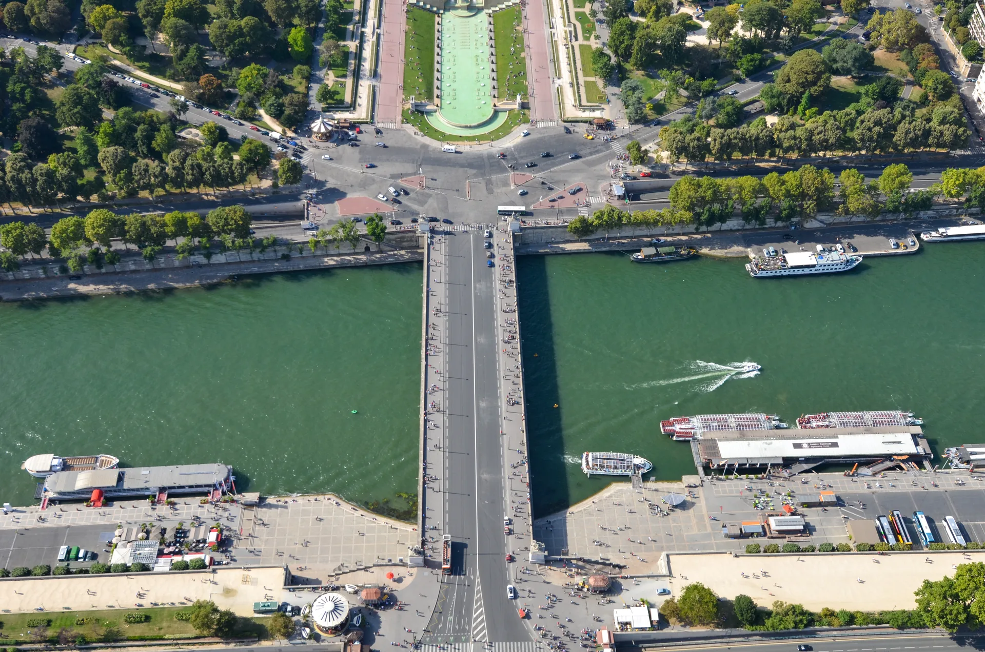 Vista aérea da Pont d'Iéna sobre o rio Sena, com barcos e os jardins do Trocadéro ao fundo, em Paris